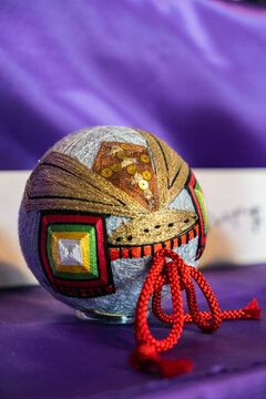 Close up of a traditional red Kaga Temari handball with intricate colorful geometric silk thread embroidery on display