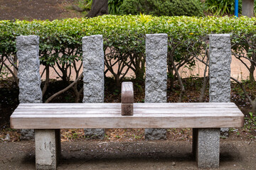 Naklejka premium empty wooden park bench with stone supports outdoors