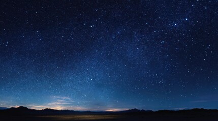Fototapeta premium Stars shine bright in the night sky over a vast landscape with mountains under clear conditions during a calm evening