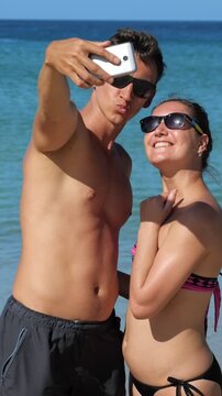 Caucasian Couple Taking Beach Selfie Travel, Playful Poses With Smartphone And Turquoise Ocean Backdrop, Sunglasses And Kissy Faces, Social Content Vibe, Youthful Vacation Energy, Travelers Enjoying
