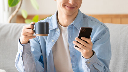 スマートフォンを見ながらコーヒーを飲む男性のライフスタイルイメージ, Man Using Smartphone While Drinking Coffee © Trickster*