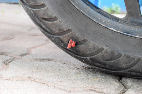 A tubeless motorcycle tire that was patched after being punctured by a sharp object.
