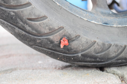 A tubeless motorcycle tire that was patched after being punctured by a sharp object.
