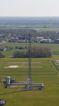 Aerial view of the NAM Grijpskerk UGS facility featuring a tall flare stack and industrial pipelines surrounded by green fields and rural landscape in Grijpskerk, Groningen, Netherlands.