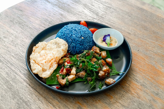 Thai stir fried chicken pad krapow with blue butterfly pea rice and crispy crackers healthy bowl
