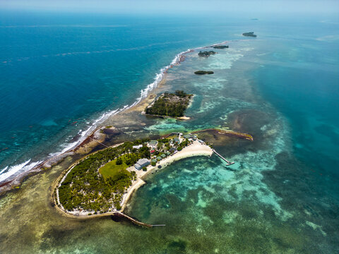Aerial view of a tropical island chain with turquoise waters, coral reefs, and lush green vegetation under a clear blue sky Guanaja, Bay Islands Department, Honduras.