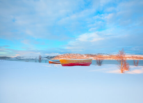 Red wooden boat covered with layers of snow - Beautiful winter landscape with snow covered red house - Tromso, Norway