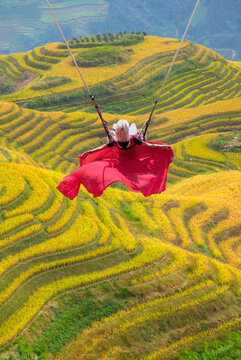 Beautiful young blond girl swing over the green rice terrace fields - Terraced rice fields, Longshen near Guilin, Guangxi Province, People's Republic of China