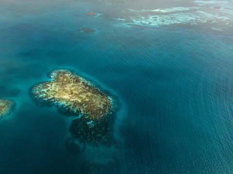 Aerial view of vibrant coral reefs and turquoise ocean waters under bright sunlight Guanaja, Bay Islands Department, Honduras.