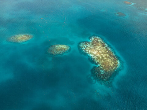 Aerial view of coral reefs and turquoise ocean water under bright sunlight Guanaja, Bay Islands Department, Honduras.