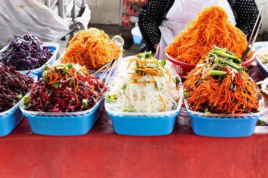 Colorful shredded vegetable salads piled high in blue trays at Siab bazaar in Samarkand. Vibrant street food display ideal for travel and culinary content.
