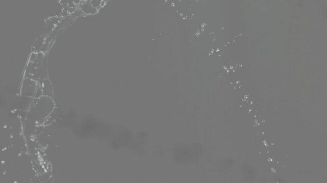 Propelled liquid sheet arcing from upper-left, thinning and breaking into drops by surface tension