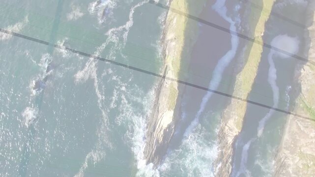Drone tilting, camera rotating, rocky headland shifting, waves crashing, showing coastal geology