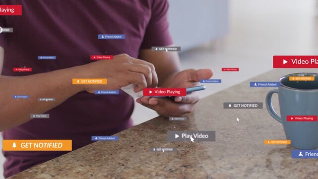 Man wiping phone in kitchen while play button appearing and generating tech tags for checking
