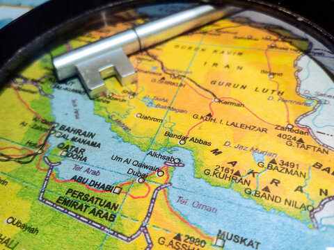 Silver metal key placed on a map of United Arab Emirates, Qatar, and Iran.