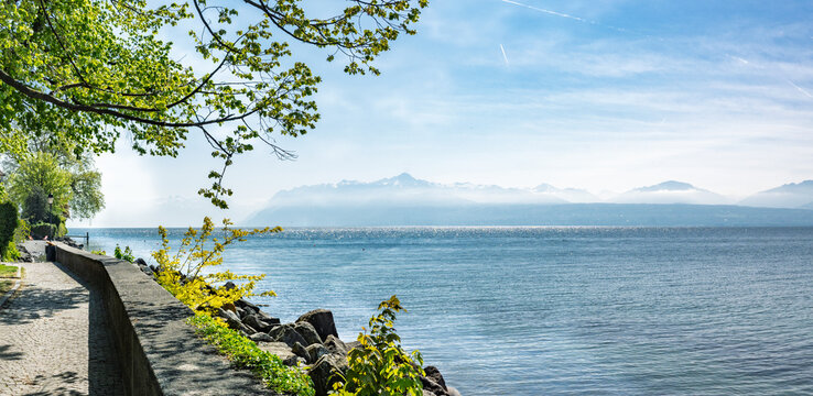 Promenade ombrag&eacute;e au bord du lac L&eacute;man avec vue sur les Alpes et un ponton, Saint-Prex, Suisse