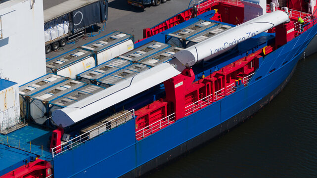 Drone view of a bulk carrier with folded VentoFoil wind propulsion at dock, showing fuel saving maritime technology, ventilated wingsails, and sustainable shipping.