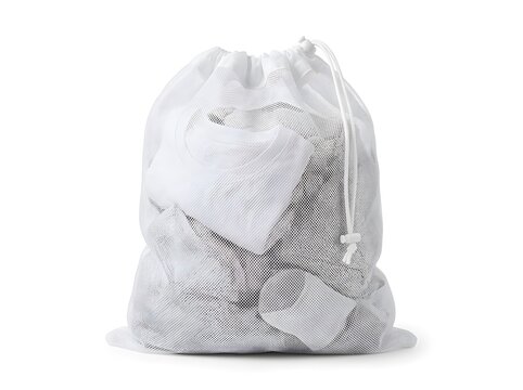 A mesh laundry bag filled with white clothing sits on a flat surface. The bag is tied with a drawstring and is prepared for a wash cycle in a laundry room