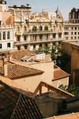 Fototapeta premium Beautiful architectural view of historic buildings with ornate balconies and terracotta rooftops in Barcelona, Spain. Sunny day in the Eixample district with classic Mediterranean facades