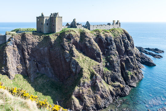Dunnottar Castle near Stonehaven in Scotland, UK: Medieval fortress ruins standing on a steep grassy cliff above the sea, creating a dramatic coastal landscape with rugged scenery and open views