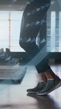 Vertical video: Female exerciser tapping heels then hopping in gym, via UI cues for cardio training