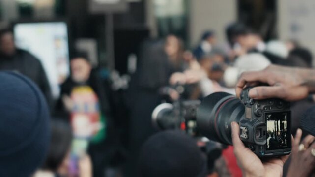 Photographer shooting video at a crowded media event