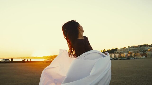 Sunset dance by the shore in coastal town with smiling woman enjoying the moment