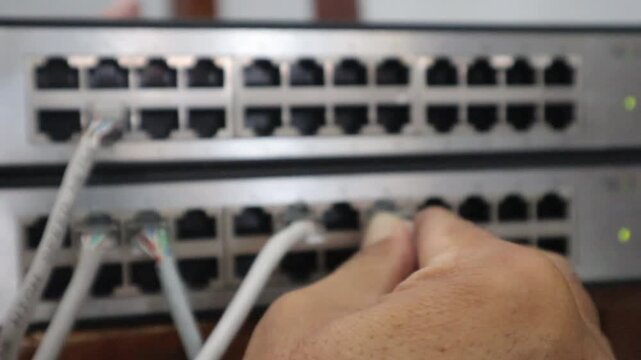 Hand connecting a network cable to a switch