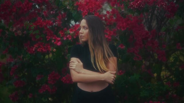 Woman Amidst Vibrant Bougainvillea Thicket. Standing Woman With Crossed Arms And Colorful Backdrop