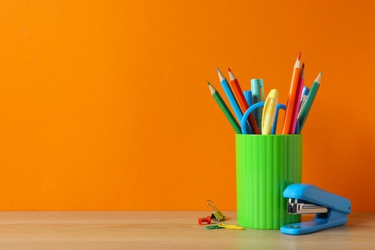 Pencil holder with school supplies on wooden table, space for text