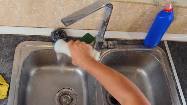 Top view of a man adding cleaning powder to a kitchen sink before scrubbing, preparing the surface for deep sanitization and removing grime. Home cleaning, sink cleaning, household hygiene