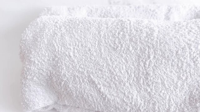 Fresh laundry towels neatly folded in white stacks on wooden table. Clean home textile care concept with soft bathroom linens ready for storage.