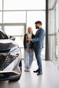 Salesman presenting new car to young customer