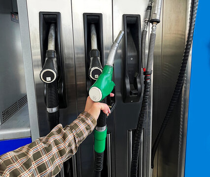 Manguera de surtidor de gasolina self service gas station con mano para repostar y llenar tanque de dep&oacute;sito de carburante petrol en gasolinera estaci&oacute;n de servicio y autoservicio