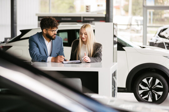 Car dealer consulting woman about new vehicle purchase