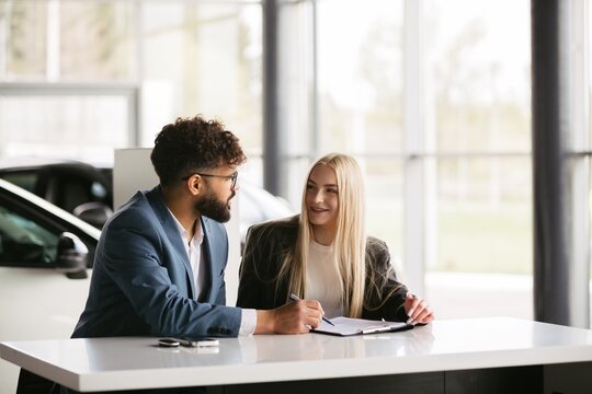 Man and woman discussing car purchase deal in dealership