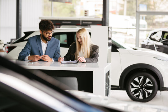 Man and woman signing new car purchase contract