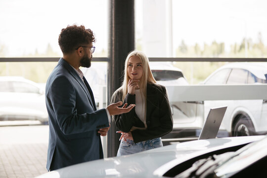 Salesman talking with customer in car showroom
