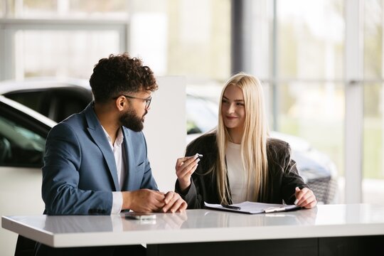 Client receiving car key from saleswoman at dealership