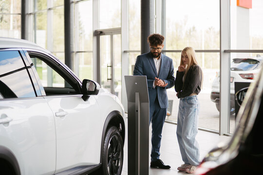 Salesman discussing new car features with customer