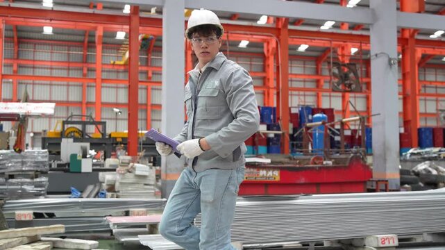 Warehouse operations worker handling metal sheets industrial facility photography bright environment ground level labor and safety