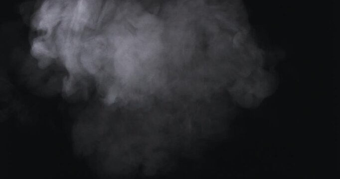 Dense white smoke billows and swirls dramatically against a pitch-black background, creating an atmospheric and mysterious cloud formation.