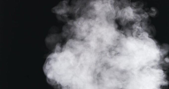 Thick white smoke rises and expands against a deep black background creating a dramatic effect.