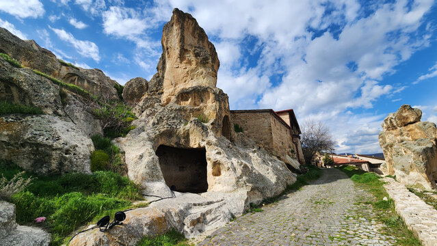 Ayazini Village (Afyonkarahisar) showing the integration of modern stone houses with ancient rock-cut formations, where traditional dwellings are built against volcanic tuff cliffs