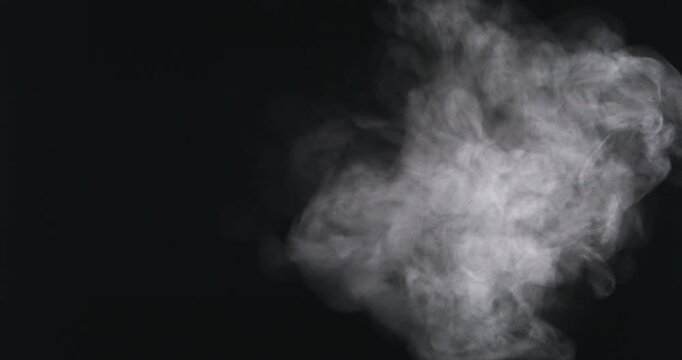 Dense white smoke billows and swirls dramatically against a pitch-black background, creating an atmospheric and mysterious cloud formation on the right side of the frame.