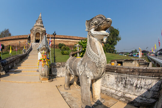 A majestic ancient Singha or lion guardian statue standing in front of the staircase at Wat Phra That Lampang Luang.