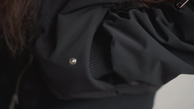 Woman checks keys. Closeup of woman seeking keys in coat pocket. Rainy street scene showing woman fumbling for keys in coat. Woman hesitantly feels inside her jacket pocket for keys on rainy day