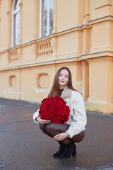 Fototapeta premium Beautiful Young Woman Holding Bouquet of Red Roses in Romantic Elegant Portrait
