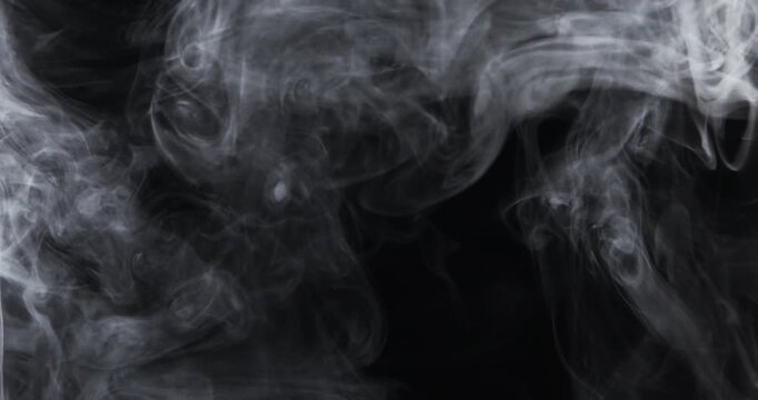 Soft flowing smoke creates elegant swirling patterns against a dark background.