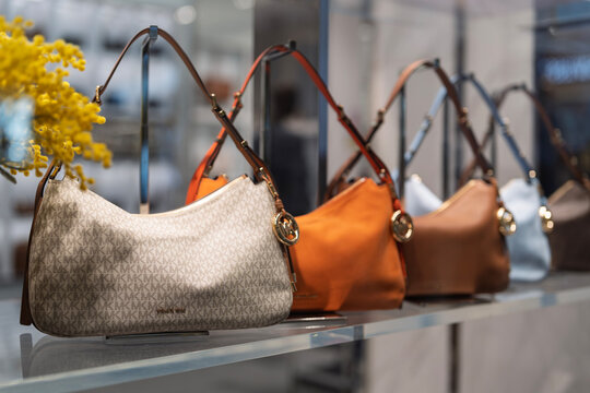 Penang, Malaysia - Apr 25, 2026: Luxury Michael Kors handbags in various designs and colors, including signature monogram patterns and solid orange and brown leather displayed in a retail store.